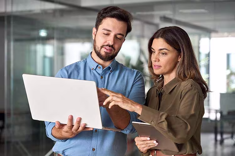 Two people in discussion while pointing at a laptop screen